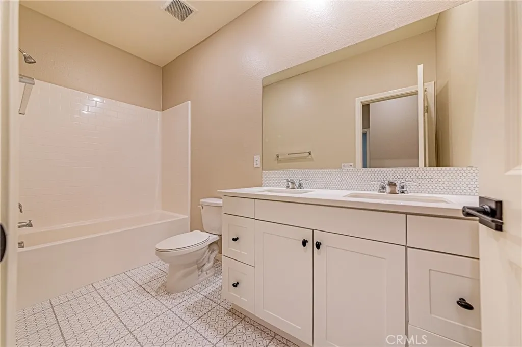 The second bathroom features custom tile flooring, a double-sink vanity, and custom cabinetry
