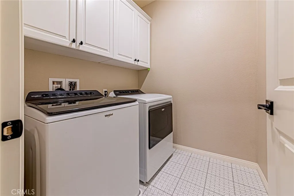The individual laundry room features custom tile flooring and includes top-quality washer and dryer units