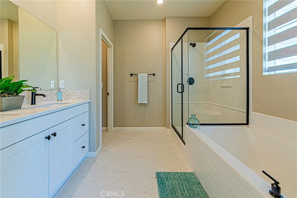 The luxurious primary bathroom features custom tile flooring, a beautifully designed bathtub, and a designer shower room with elegant finishes
