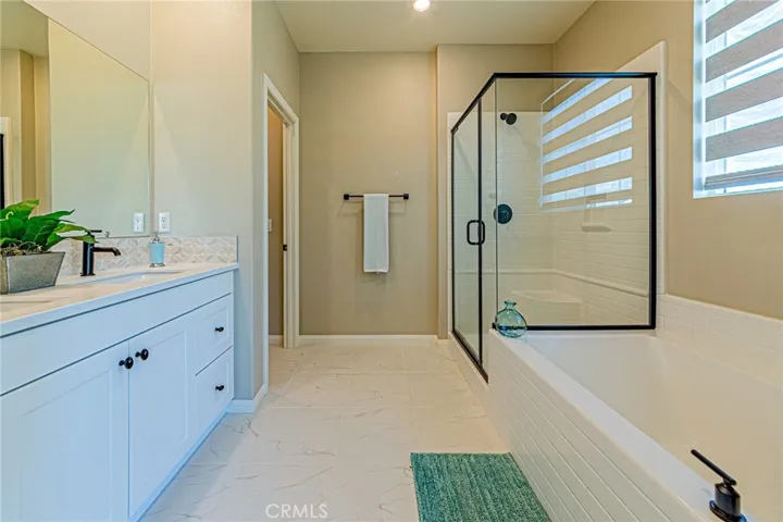 The luxurious primary bathroom features custom tile flooring, a beautifully designed bathtub, and a designer shower room with elegant finishes