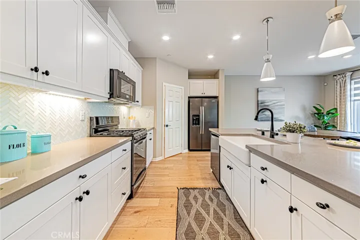 The gourmet kitchen showcases a designer custom backsplash, top-quality stainless steel appliances, and a premium refrigerator, all included with the home