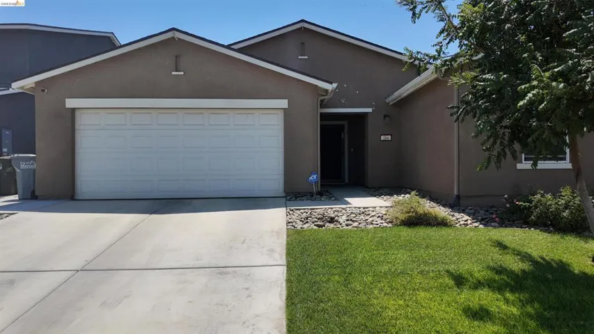 Stucco exterior with a pitched roof, attached two-car garage, concrete driveway, and front lawn