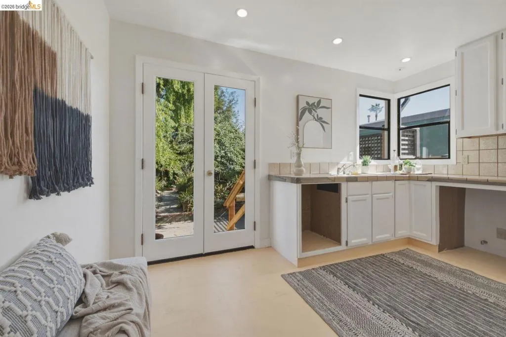 French doors opening to a lush exterior, recessed lighting, corner window, white cabinetry, and light-toned flooring