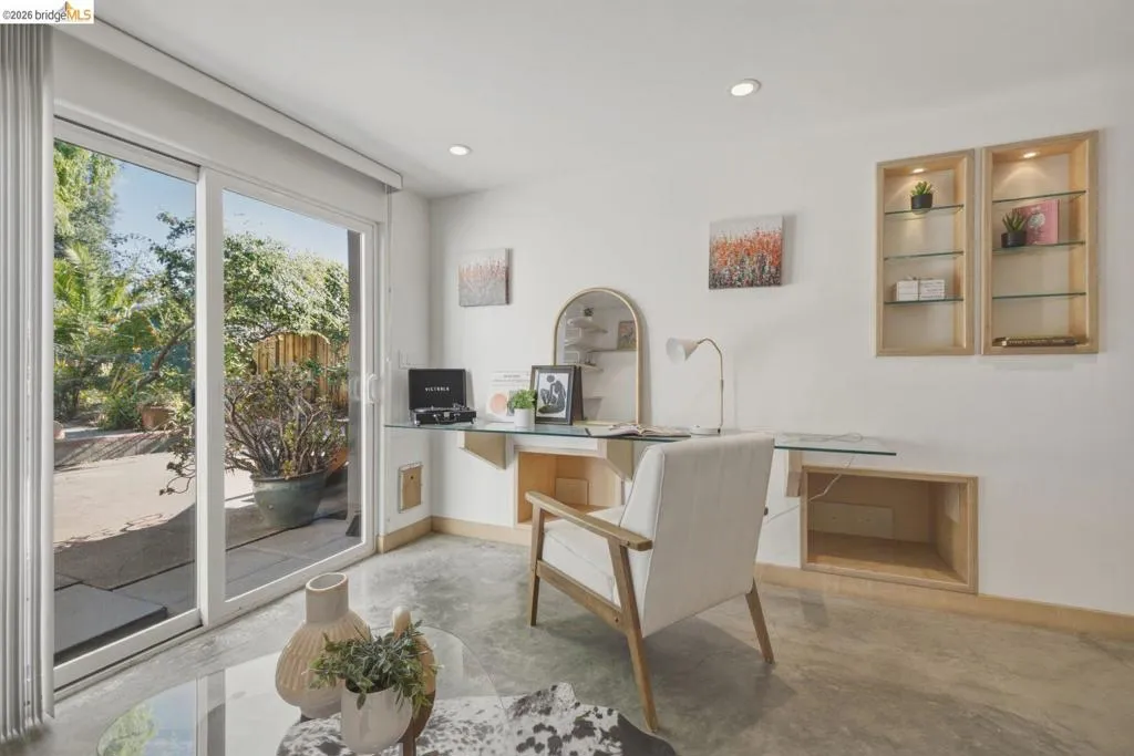 Room featuring concrete flooring, white walls, and a large sliding glass door