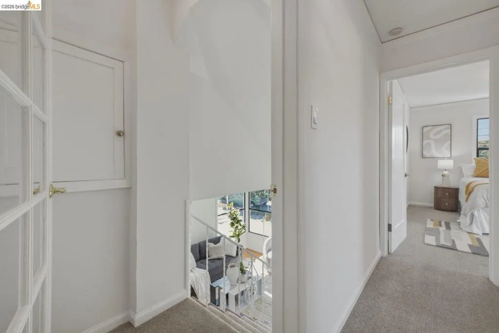 Upper-level hallway with neutral carpet flooring, white painted walls, and white trim