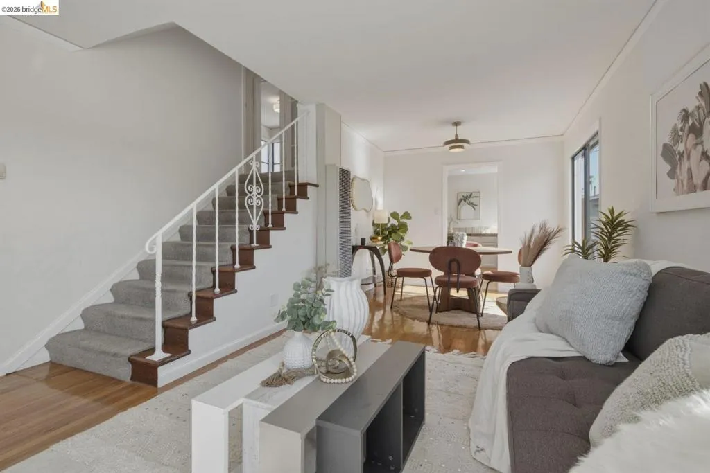 Hardwood flooring extends from the living space into a dining area featuring a modern light fixture
