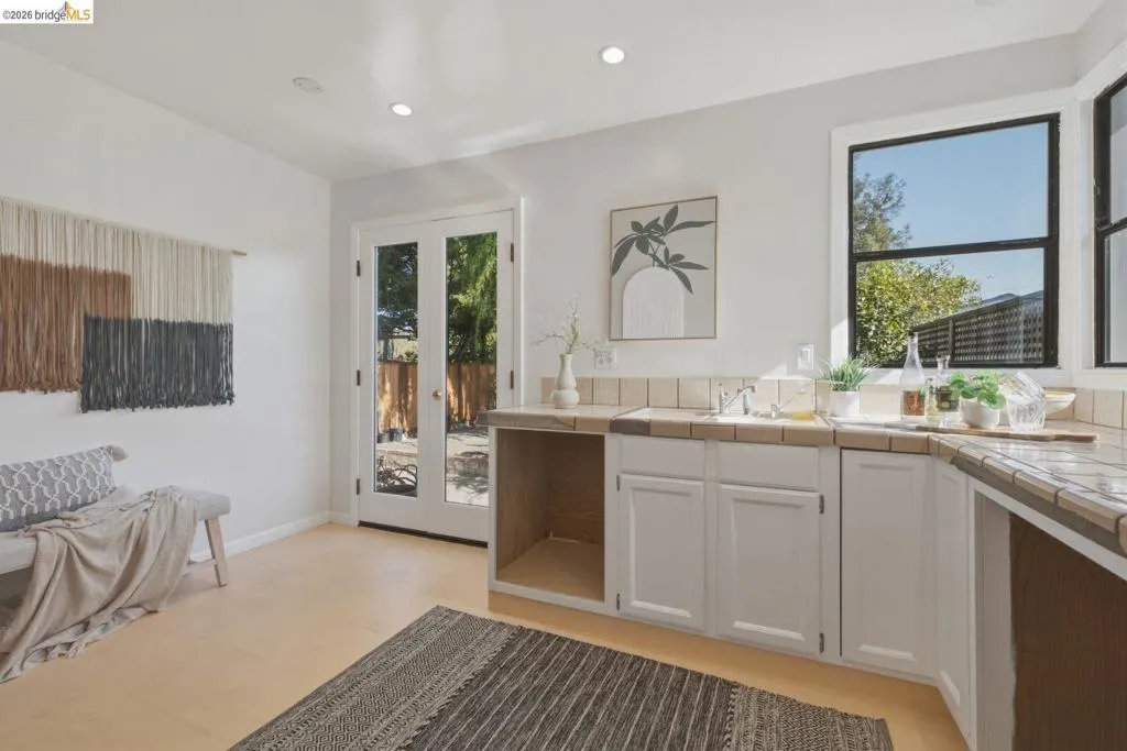 Kitchenette featuring tile countertops, white cabinetry, and a stainless steel sink