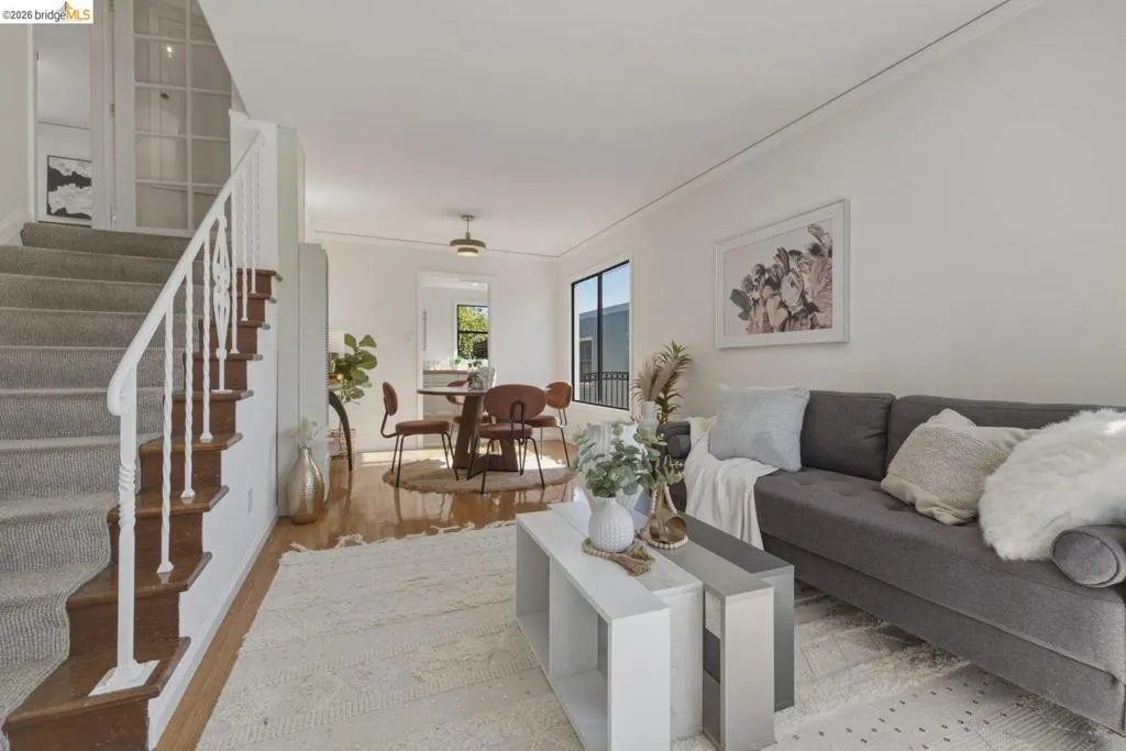 Open-concept living area with white walls and wood-finish flooring