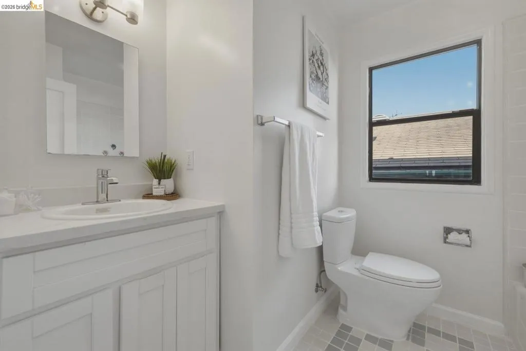 Bathroom featuring a white vanity with an integrated sink, polished chrome faucet, and rectangular mirror