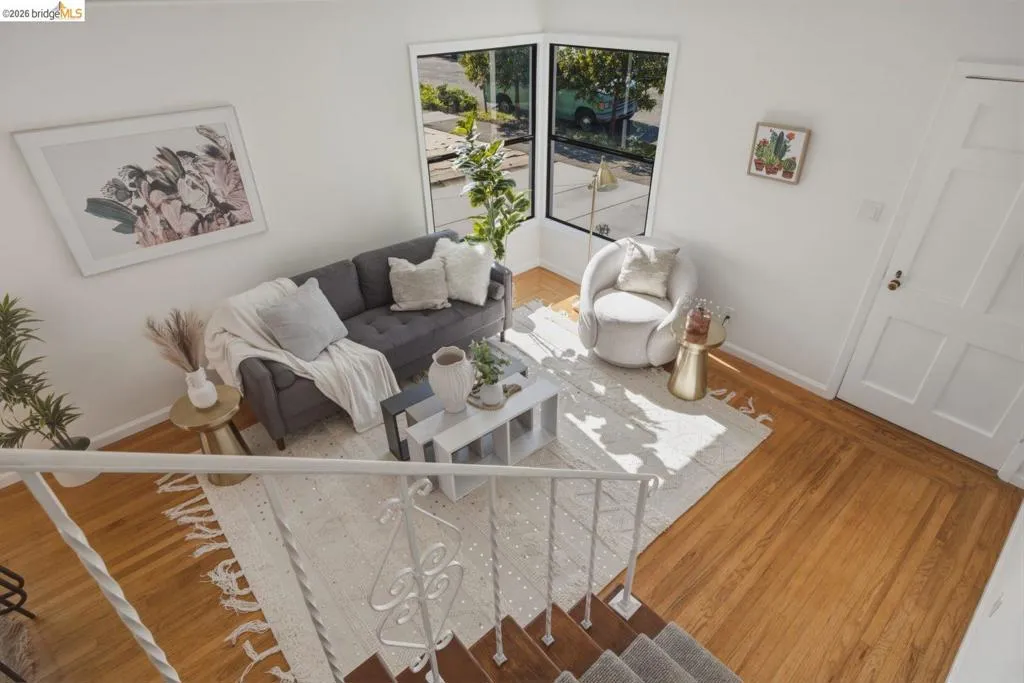Hardwood flooring in a bright living area featuring white walls, a bay window, and a paneled interior door
