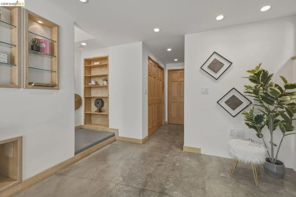 Concrete flooring with recessed lighting, built-in shelving, glass-front display cabinetry, and light wood trim