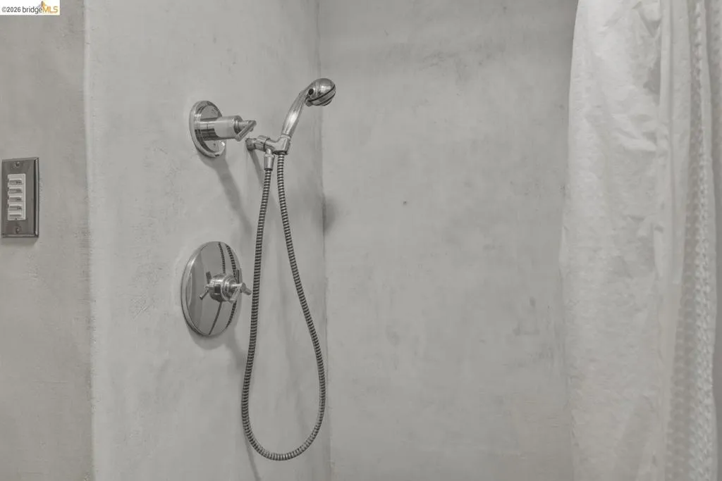 Contemporary shower with polished chrome fixtures, including a handheld shower head and an integrated control valve