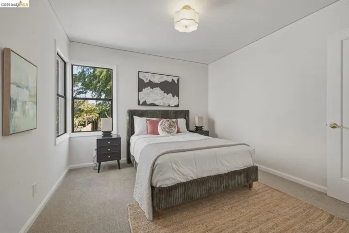 Bright bedroom featuring a flush mount ceiling light, white walls, and light-colored carpet