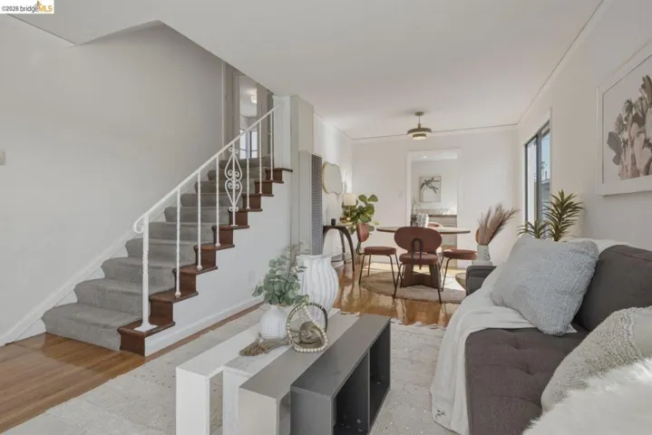 Hardwood flooring extends from the living space into a dining area featuring a modern light fixture