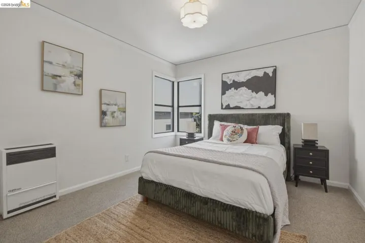 Corner window installation with white trim, carpeting, and a built-in wall heater