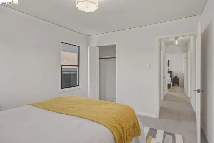 Neutral wall paint with crown molding, double-hung window with black trim, and carpet flooring