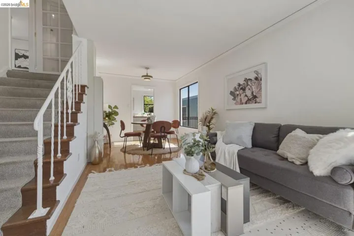 Open-concept living area with white walls and wood-finish flooring