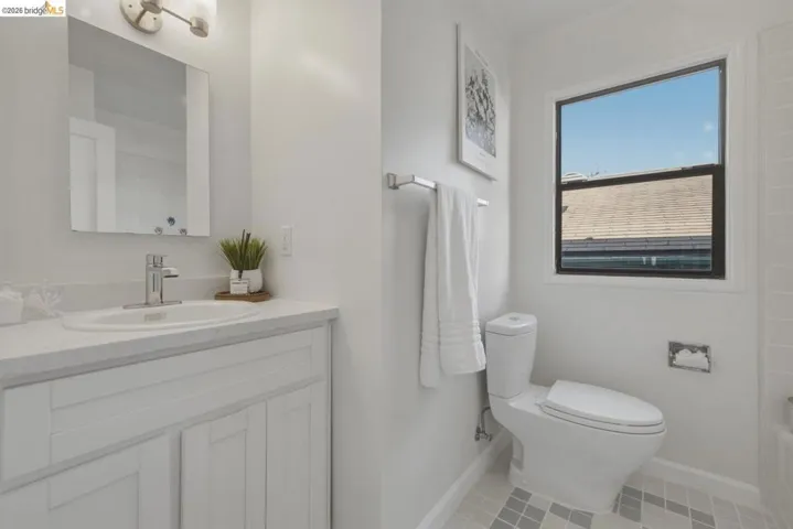 Bathroom featuring a white vanity with an integrated sink, polished chrome faucet, and rectangular mirror