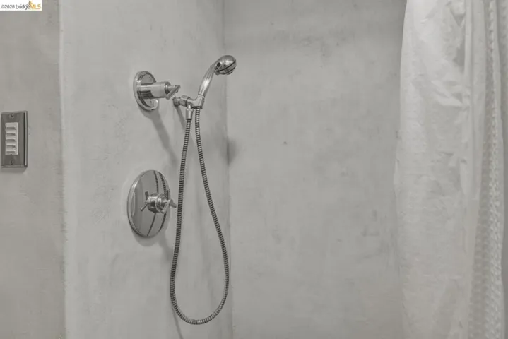Contemporary shower with polished chrome fixtures, including a handheld shower head and an integrated control valve