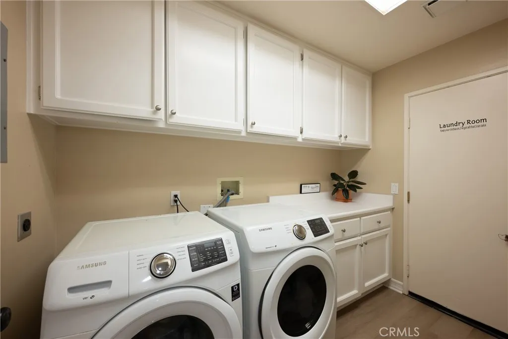The laundry room is located downstairs with a counter for folding and white cabinets. The laundry room is located downstairs with a counter for folding and white cabinets.