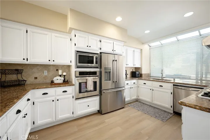 The gorgeous updated kitchen has white cabinets and stainless steel appliances.