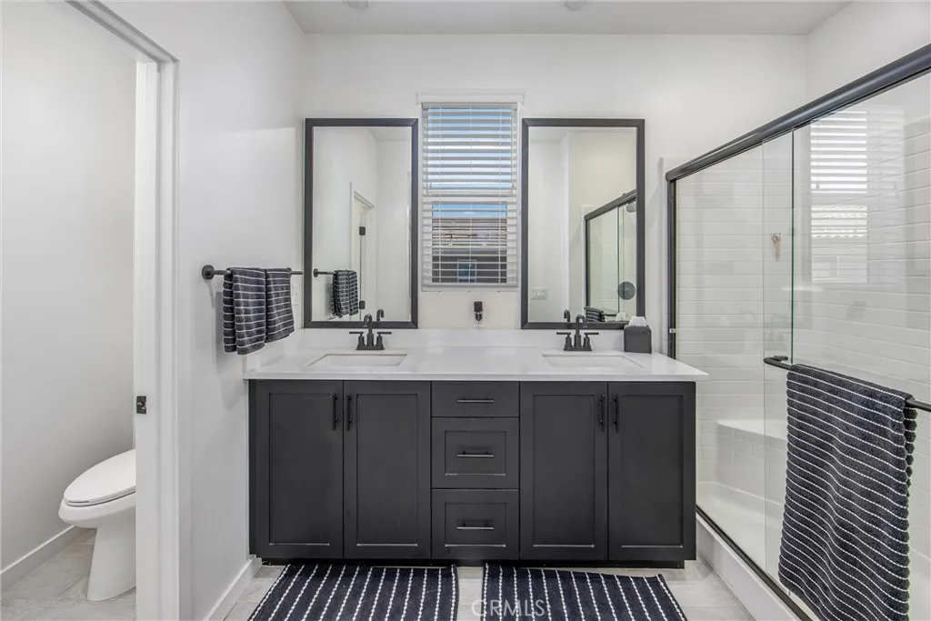 Primary bathroom offering dual sinks, generous counter space, and a glass-enclosed shower