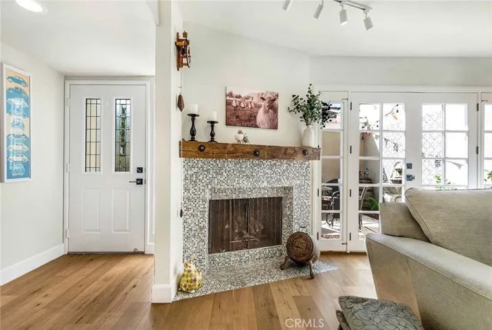 Living room fireplace with mosaic tile surround and thick wood mantel.