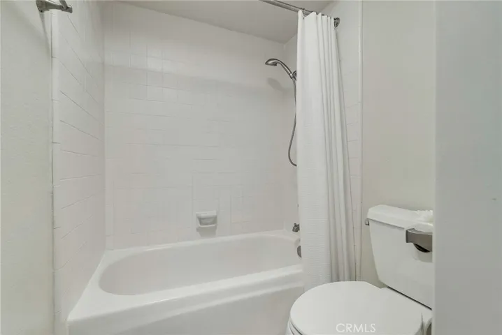 Upstairs bathroom private toilet area and shower in tub.