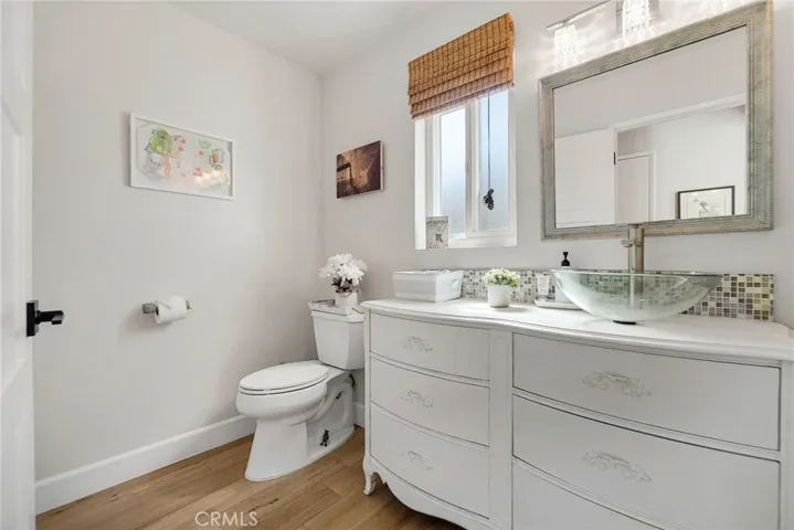 Downstairs half bath with vanity, mirror, vessel sink, toilet and dual pane window.
