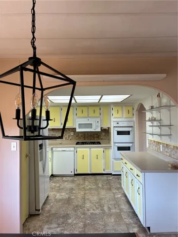 Loking westerly to 
gas stove double oven newer rock tumbled backspash which goes al the way up to upper exhaust and wood painted sunfloweryellow and blanco