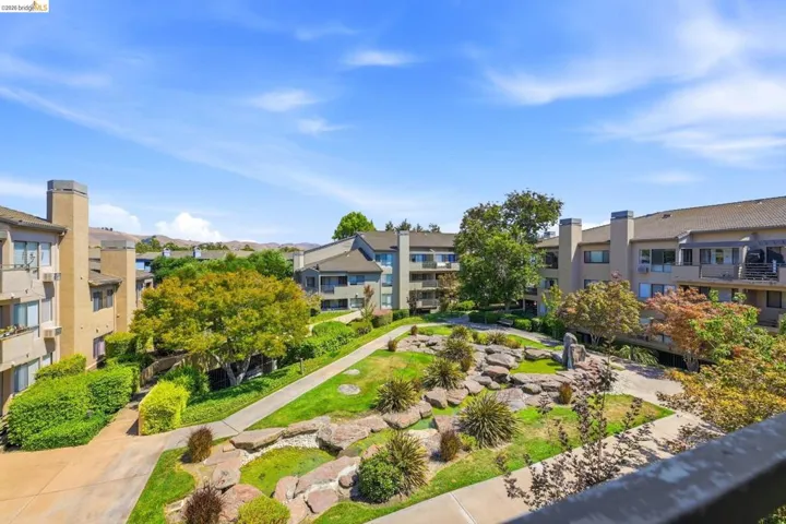 Expansive courtyard featuring a landscaped rock garden, mature trees, manicured lawns, and paved walkways