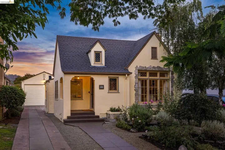 Tudor-style architecture featuring a stone facade, dormer window, covered entry, and attached single-car garage