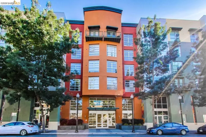 Multi-story building facade with varied paneling, prominent street-level entryways, multiple private balconies, and extensive window arrays