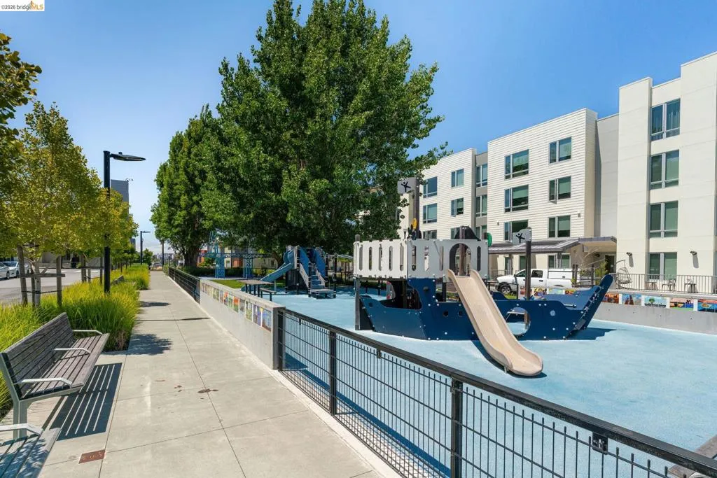 Playground area featuring a ship-themed structure with a slide, surrounded by a black metal fence
