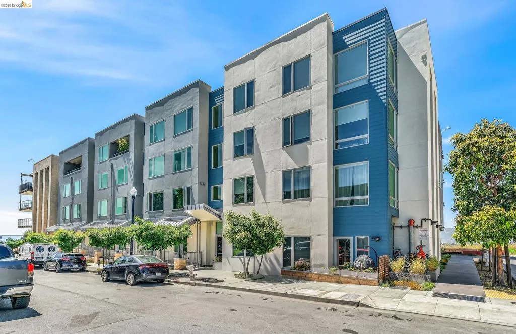 Contemporary multi-story building featuring a facade of light-toned stucco and prominent blue paneling