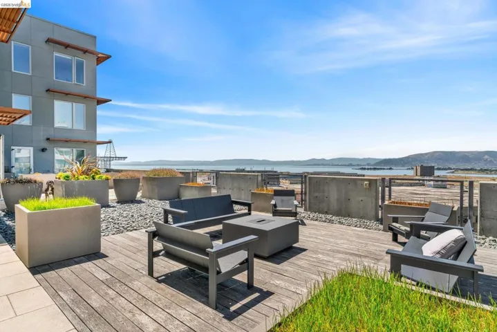 Expansive rooftop deck featuring wood-finish decking, concrete planters, and a built-in fire pit