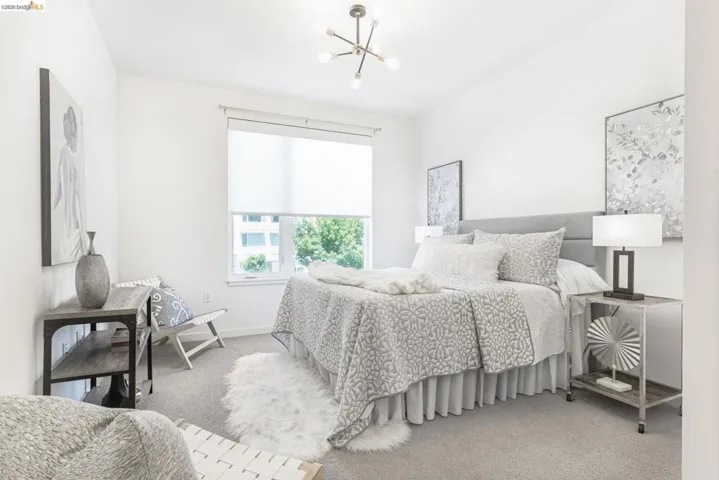 Bedroom featuring a single window, roller shade, and light gray carpet flooring