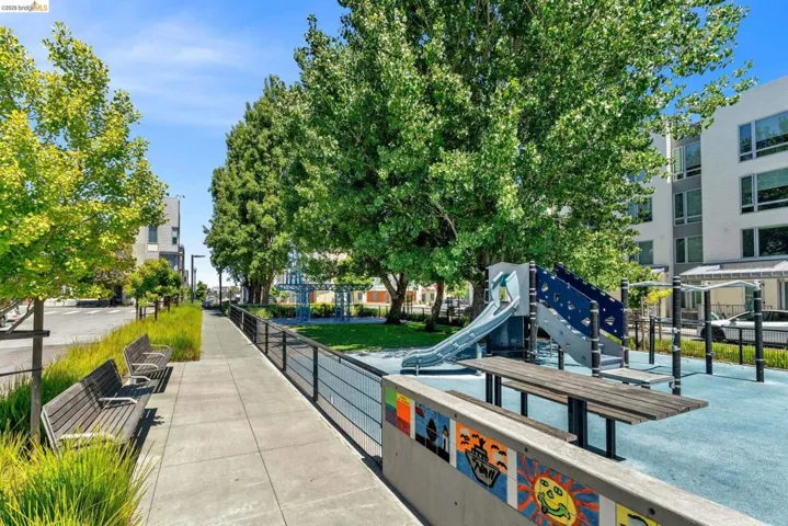 Outdoor recreation area featuring a playground with a slide, climbing wall, and soft blue ground covering
