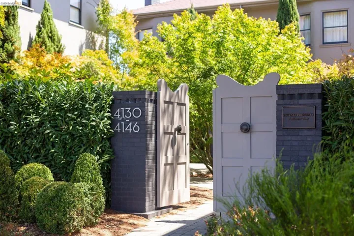 Gated entry with dark brick pillars and decorative white gates
