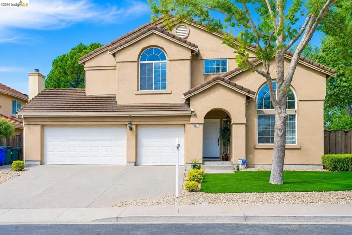 Stucco exterior with arched windows, a two-car garage, and a tiled roof