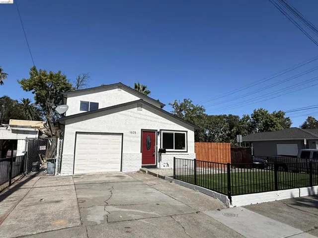 Stucco exterior with a pitched roof, attached garage, and a red entry door