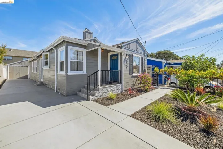 Siding exterior with white trim, a blue entry door, and an entryway with a black railing
