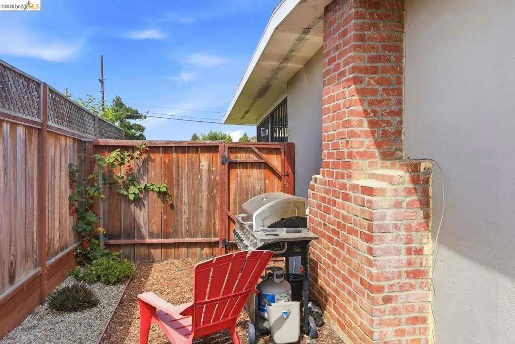 Private outdoor area featuring wood fencing, a brick architectural element, and a gravel ground cover