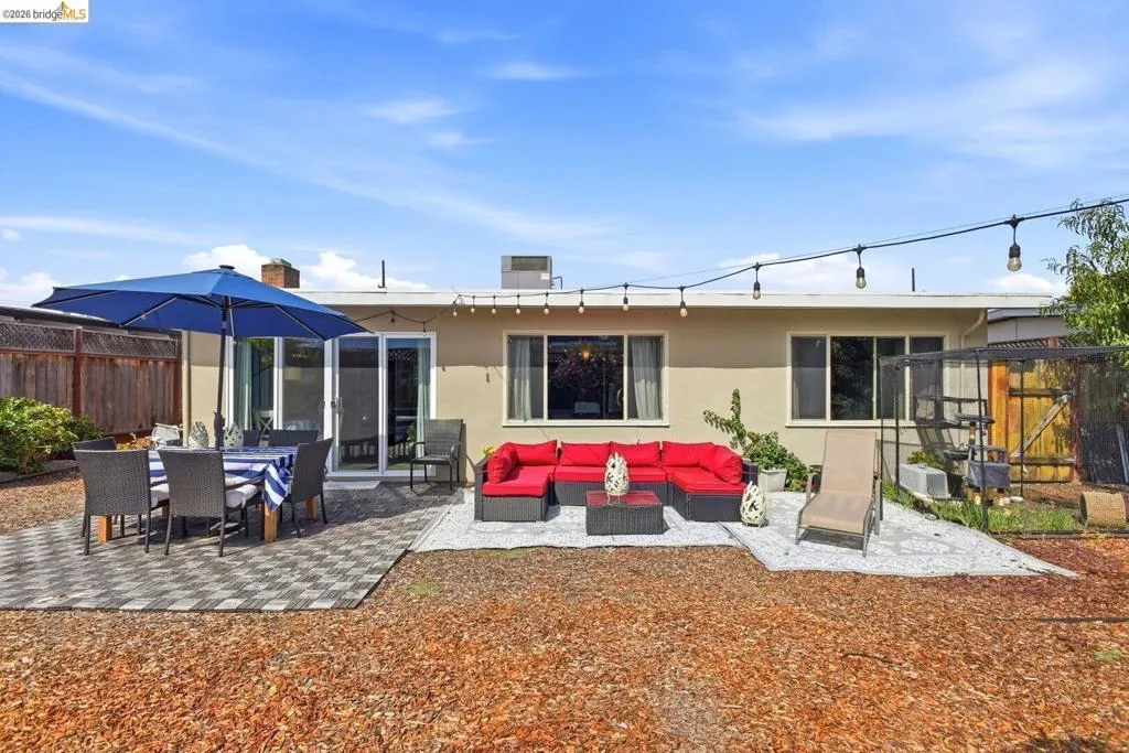 Spacious backyard featuring multiple patio areas, a privacy fence, and string lighting