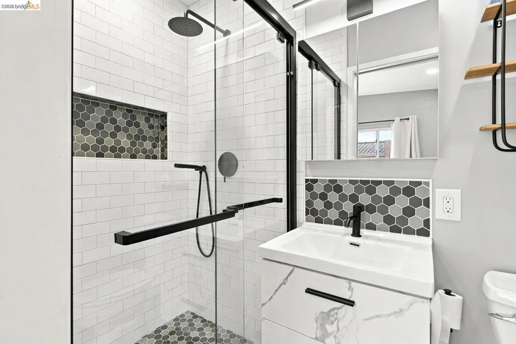 Shower with black-framed glass enclosure, rain shower head, and built-in niche
