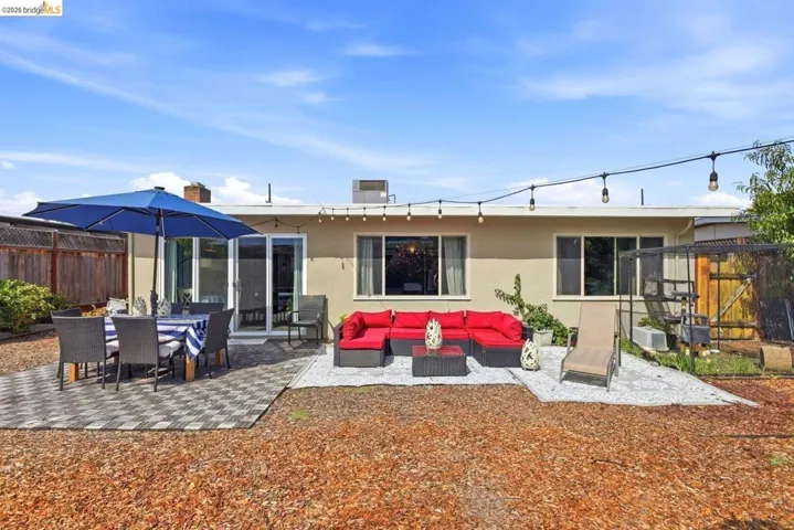 Spacious backyard featuring multiple patio areas, a privacy fence, and string lighting