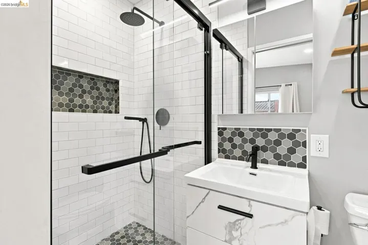 Shower with black-framed glass enclosure, rain shower head, and built-in niche