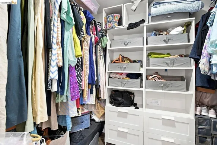 Built-in closet system featuring multiple hanging rods, open shelving, and integrated drawers