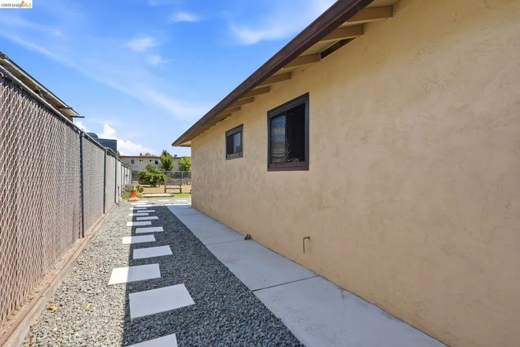 Stucco exterior with brown trim, covered eaves, and a concrete walkway