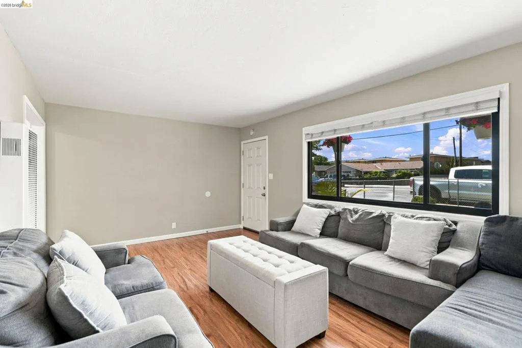 Recessed lighting, wood-finish flooring, white trim, and a large picture window with white blinds